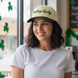 Woman wearing a 'Feeling Lucky' cap in a festive indoor setting with shamrock decorations.